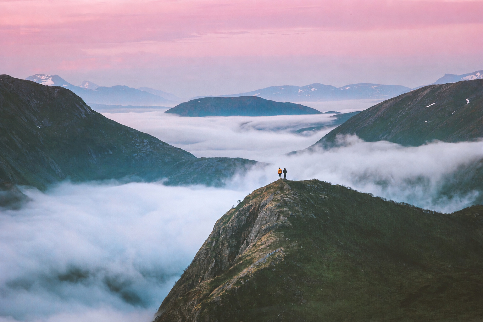 Two figures standing on a mountain ridge above a sea of cloud at dawn, the liminal space between one chapter and the next